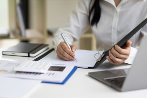 La secretaria escribe la nota del mensaje de trabajo en el expediente.